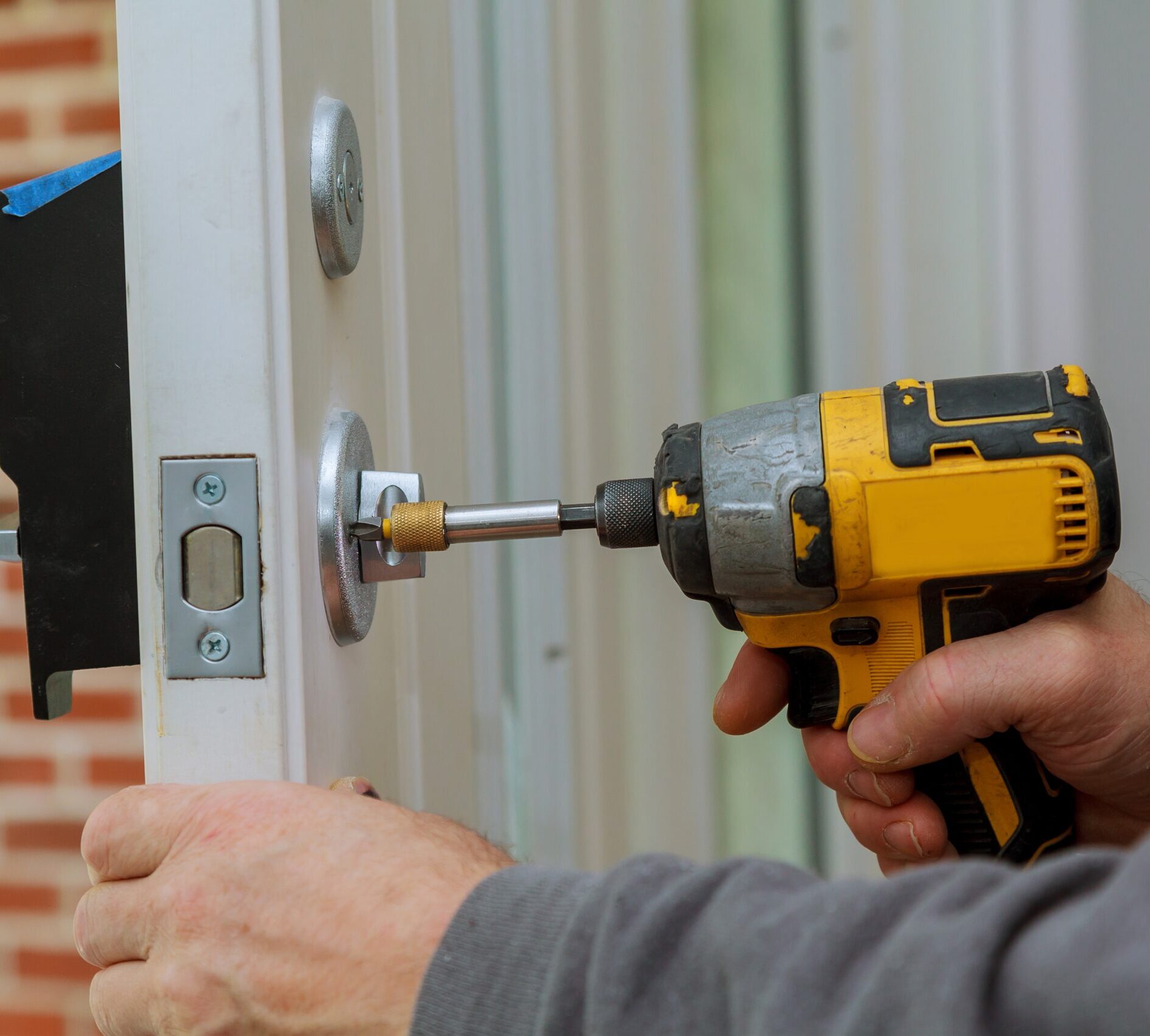 Install the door handle with a lock, Carpenter tighten the screw, using an electric drill screwdriver, close-up.