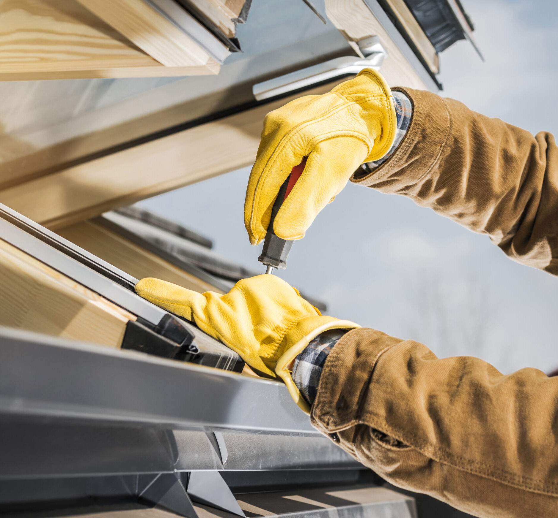 Modern European Style Wooden Roof Window Installation Performed by Professional Worker Close Up. Adjusting Elements with a Screwdriver.