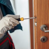 Locksmith workman in uniform installing door knob. Professional repair service. Maintenance Concept